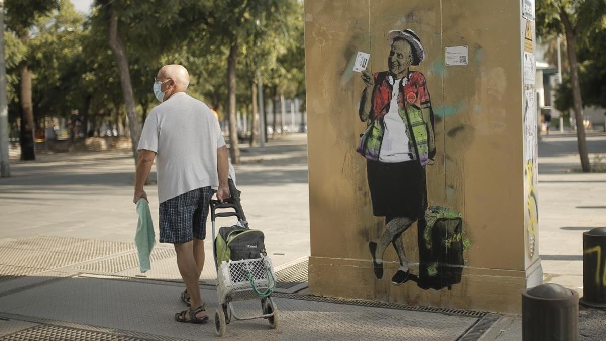 Un hombre pasa delante del dibujo de TVboy del rey emérito Juan Carlos I en el parque de la Barceloneta, el 20 de agosto del 2020