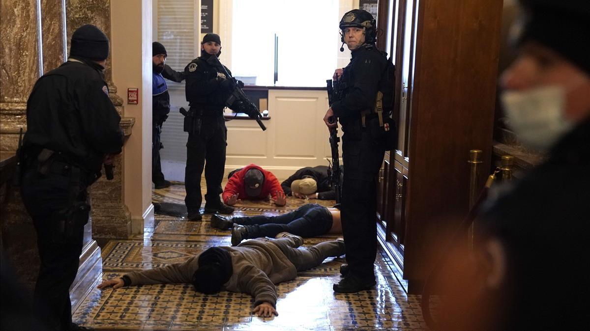 Agentes de la policía reducen a los manifestantes que han asaltado el Capitolio.