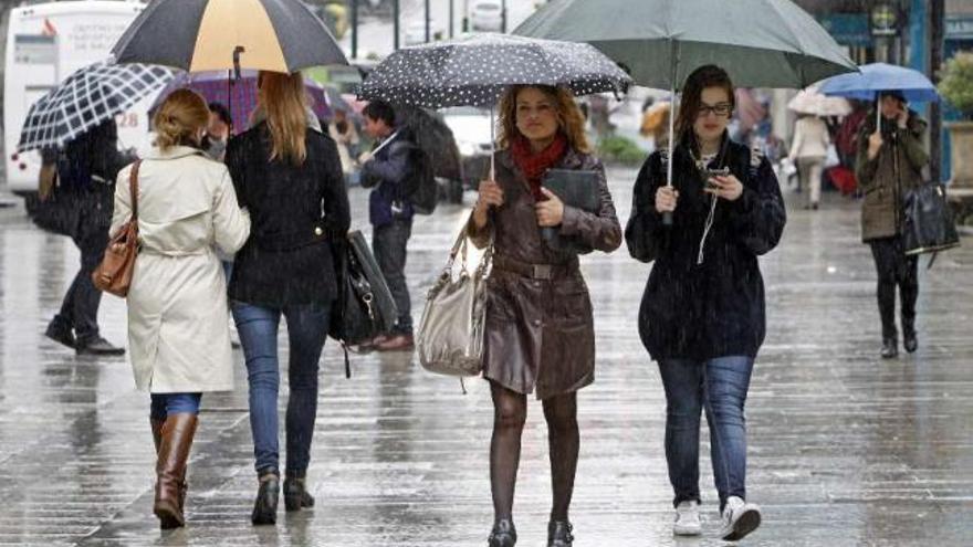 Los transeúntes se cubren con paraguas, ayer, en la calle Príncipe.  // Marta G. Brea