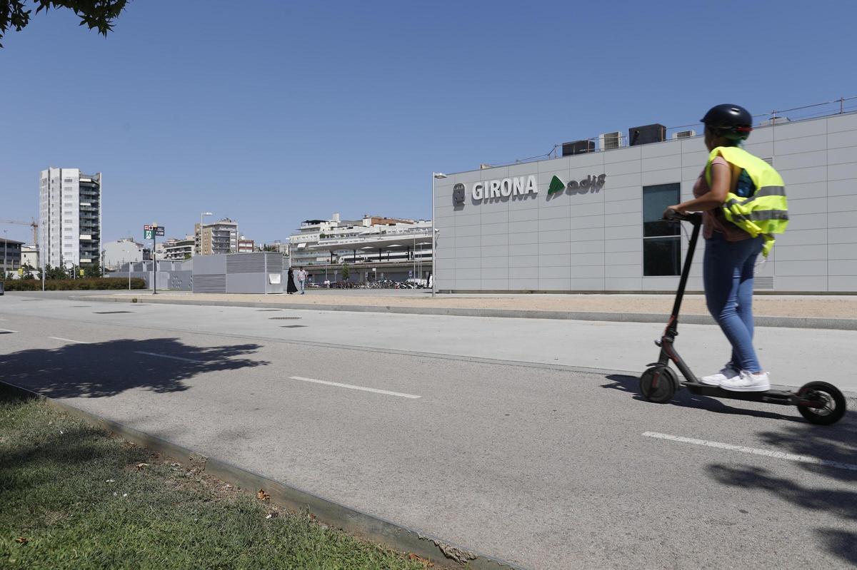 Una usuària de patinet elèctric pel carril bici del parc Central de Girona, amb casc.
