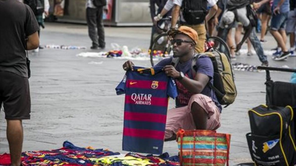 Un hombre vende camisetas falsificadas del Barça, en el Maremágnum, ayer.