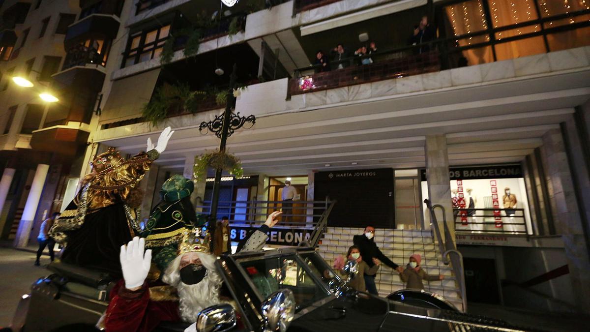 Los Reyes Magos de Oriente saludados por varios niños desde un balcón de la calle de Sant Francesc de Borja, durante su recorrido, anoche, por toda la ciudad. | ÀLEX OLTRA