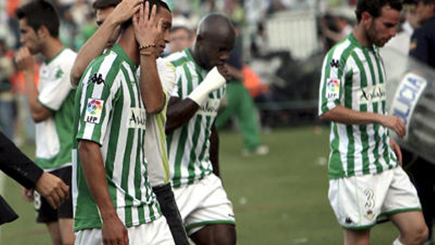 Desolación. El delantero bético Oliveira es consolado mientras se retira del estadio, junto a sus compañeros Emaná y Fernando Vega.