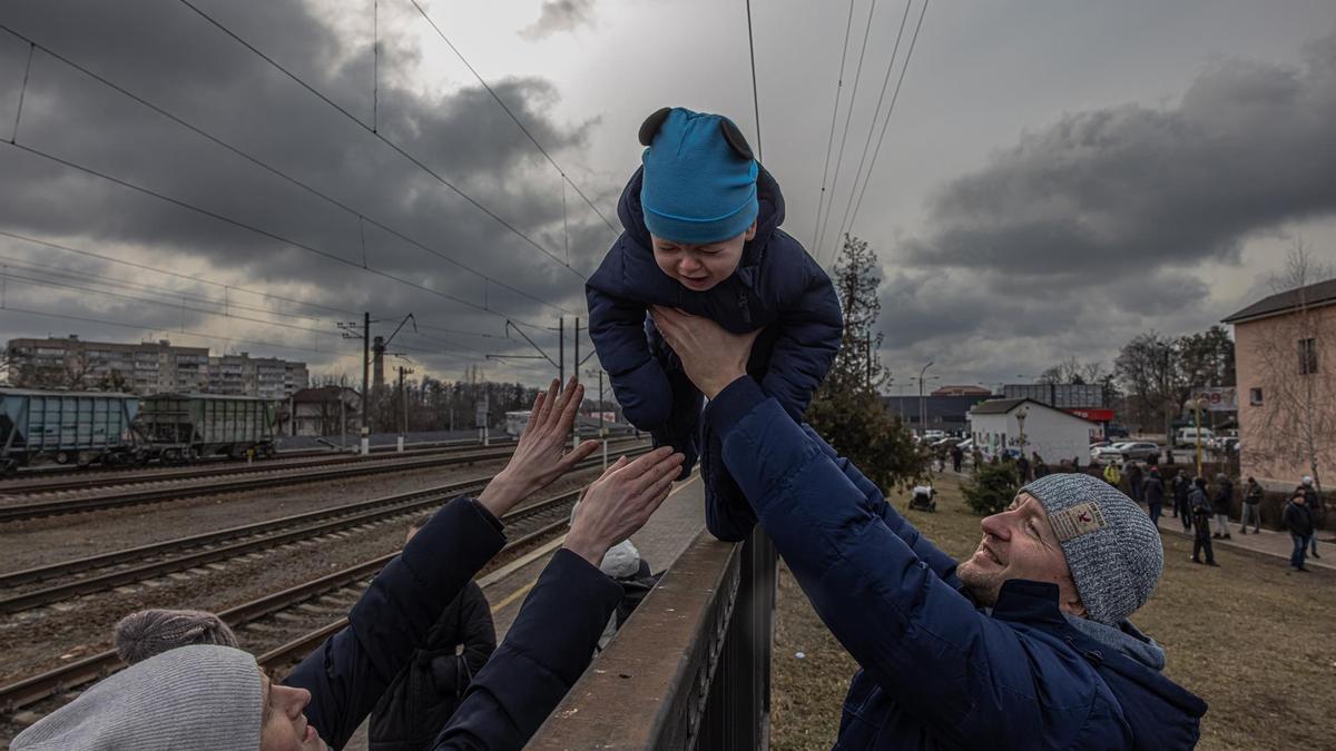 Un padre entrega su bebé a la madre en la ciudad ucraniana de Irpín antes de la llegada de un tren de evacuación