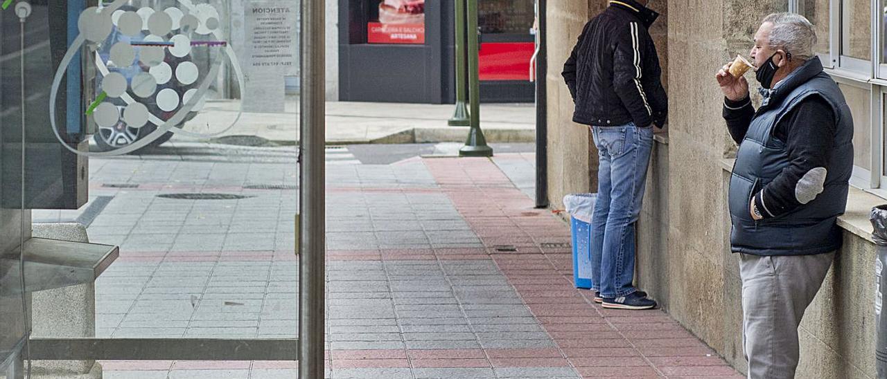 Un vecino de Verín se toma un café para llevar apoyado en una pared en la calle.   | // CARLOS PETEIRO