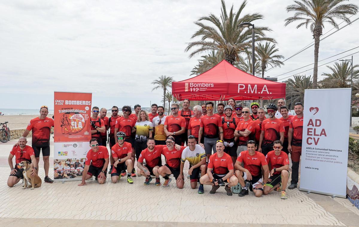 Bomberos y organizadores posan tras la línea de meta al final de la carrera.