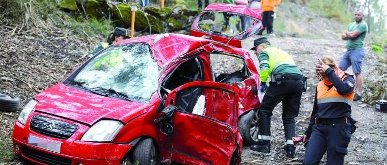 Dos agentes de la Guardia Civil inspeccionan el vehículo accidentado.