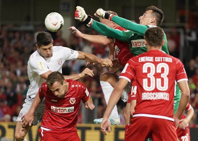 El portero del Cottbus Lennart Moser (D) y  Robert Lewandowski del Bayern Munich van a por el balón durante el partido de la Copa Alemania entre el FC Energie Cottbus v FC Bayern Munich en el Estadio Freundschaft en Cottbus.