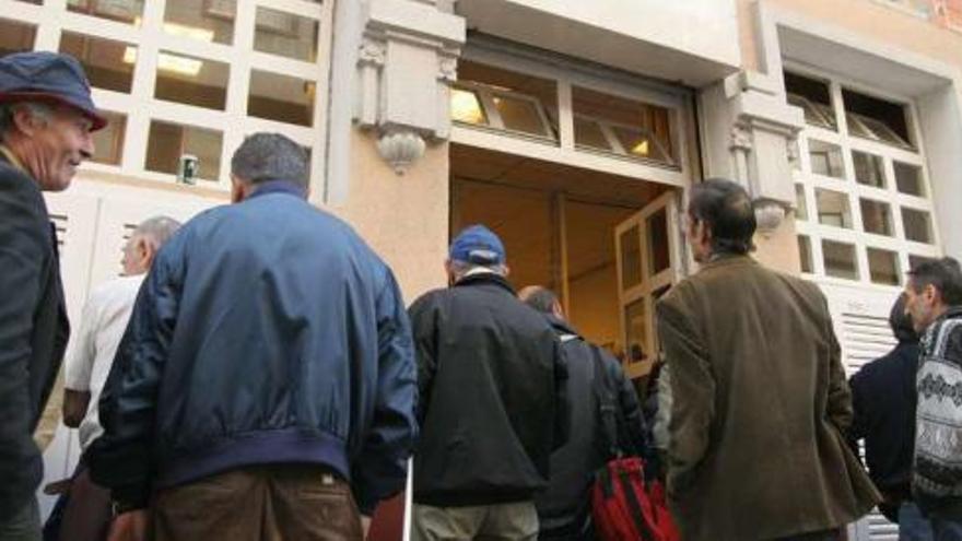 Usuarios de la Cocina Económica, ante la puerta de sus instalaciones en la calle Juan Canalejo.