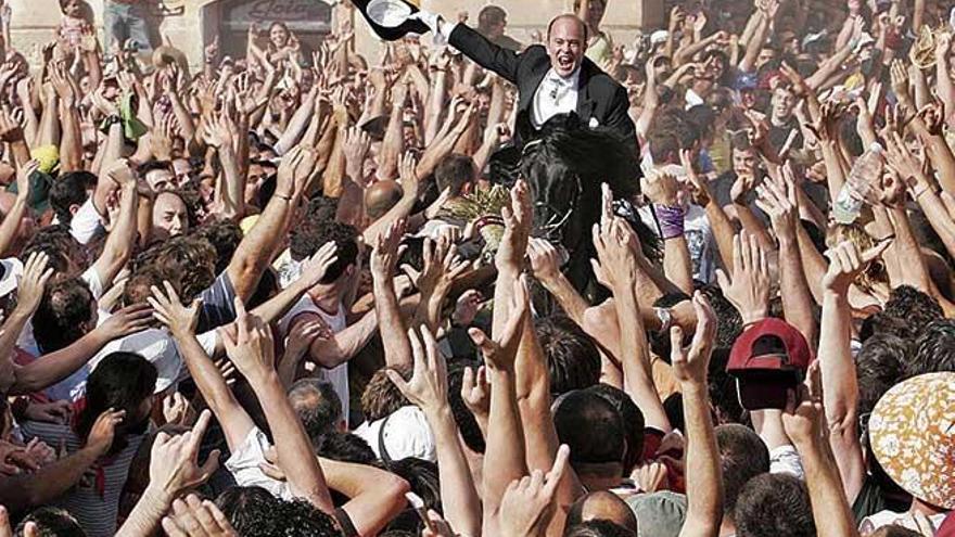 Un jinete pasa entre la multitud en Ciutadella durante las fiestas de Sant Joan.