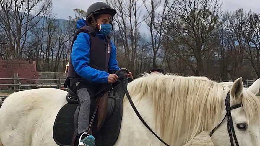 Un infant munta a cavall en una sessió d&#039;hipoteràpia