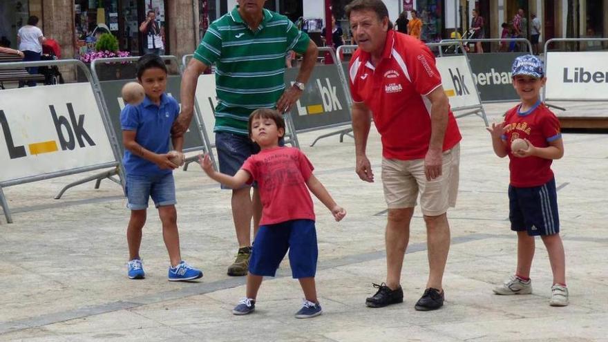 Octavio Cayado y José Manuel Costales enseñan a los chavales cómo tirar la bola.