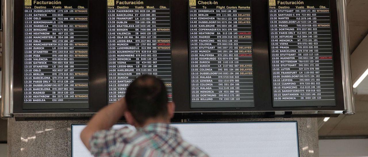 Un pasajero en Son Sant Joan ante un inquietante panel de cancelaciones y retrasos de vuelos por las huelgas de julio.