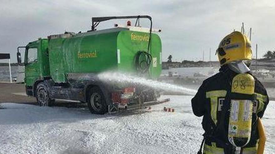 n bombero lanza espuma contra un camión de combustible que iba a descargar en la gasolinera pero al que se le rompió la manguera.