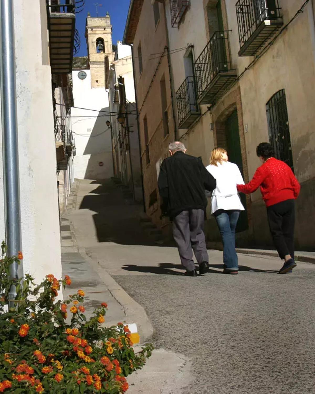Tres personas caminan por una calle en un pueblo, en una foto de archivo.