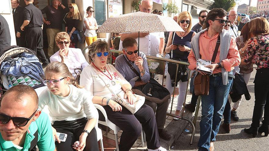 Turistas esperan el paso de la cofradía de Viñeros en la calle Carretería.