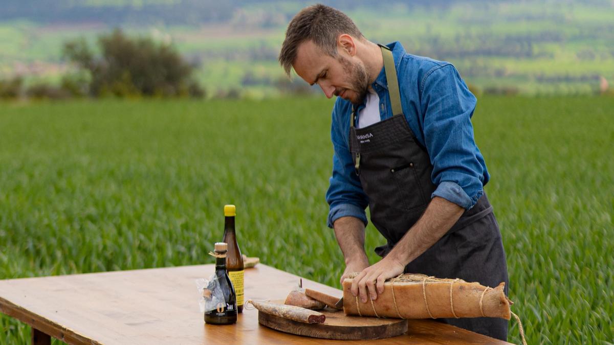 El chef Arnau París corta embutido en El Molí de la Vansa, el restaurante que solo abre en verano en la masía familiar de Boada (La Noguera).