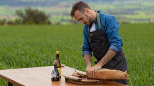 El chef Arnau París corta embutido en El Molí de la Vansa, el restaurante que solo abre en verano en la masía familiar de Boada (La Noguera).