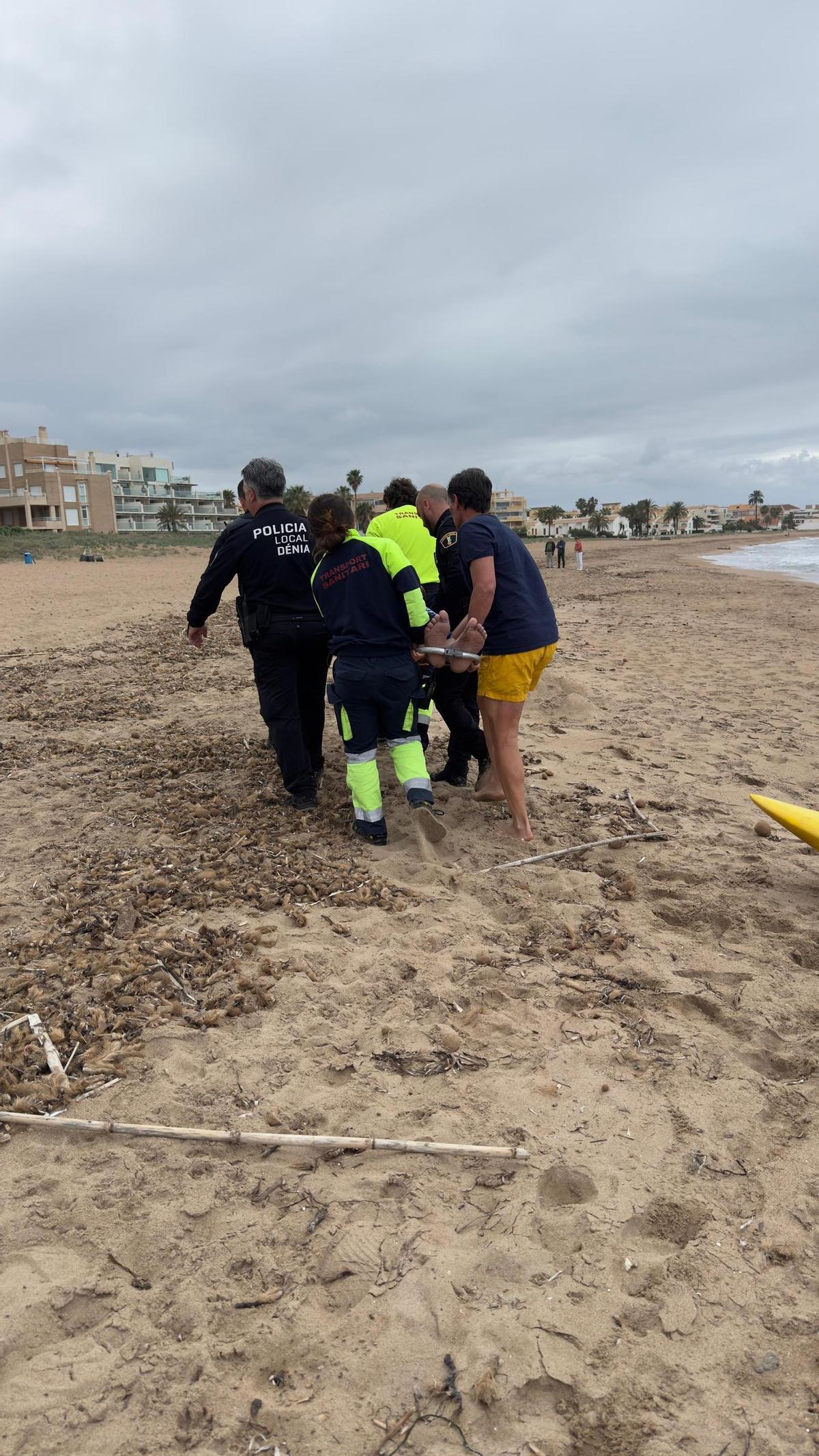 Los agentes, los sanitarios y el bombero fuera de servicio trasladan en camilla al bañista