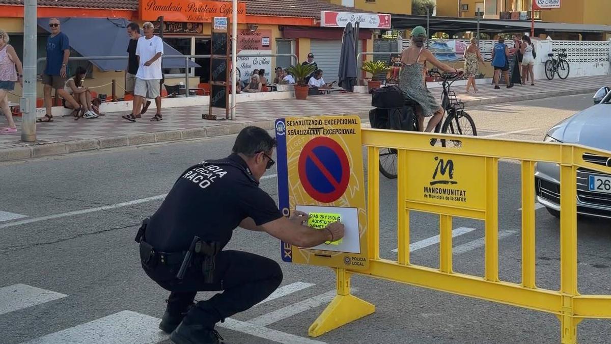 Un agent de la Policia Local de Xeraco col·loca un cartell a l'avinguda on finalitza la Volta