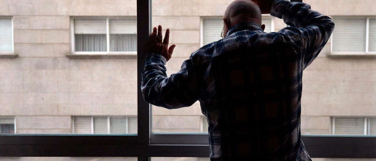 Un hombre solo mira a través de la ventana // G. Santos