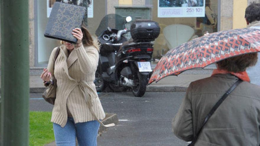 Una joven se protege de la lluvia en la calle Juana de Vega de A Coruña.