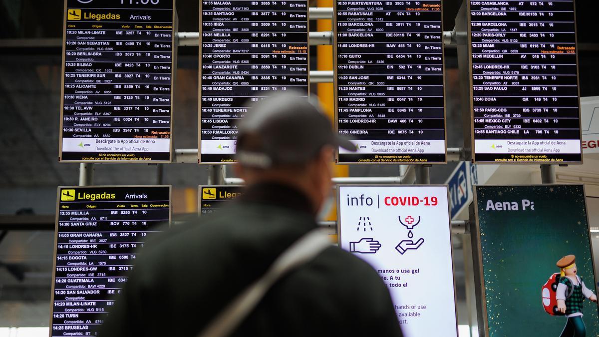 Archivo - Un hombre con mascarilla observa los paneles informativos de las salidas de los vuelos en el aeropuerto Adolfo Suárez Madrid-Barajas, a 30 de diciembre de 2022, en Madrid (España).