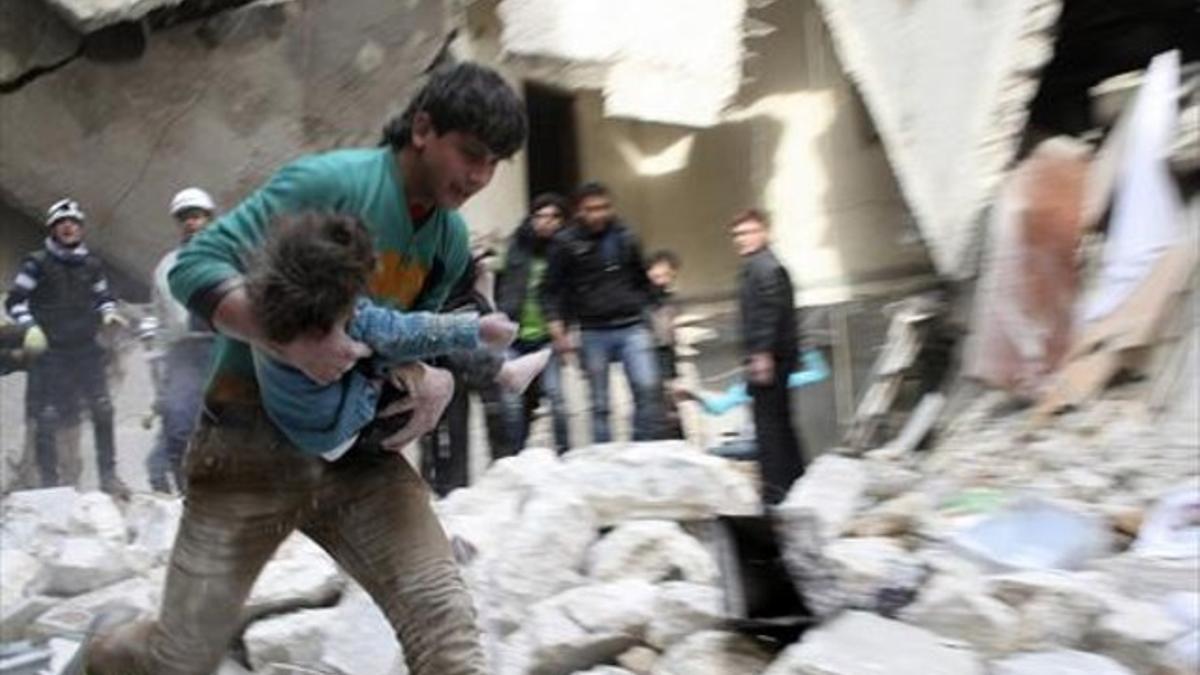 Un hombre traslada a una niña herida tras un bombardeo en Alepo.