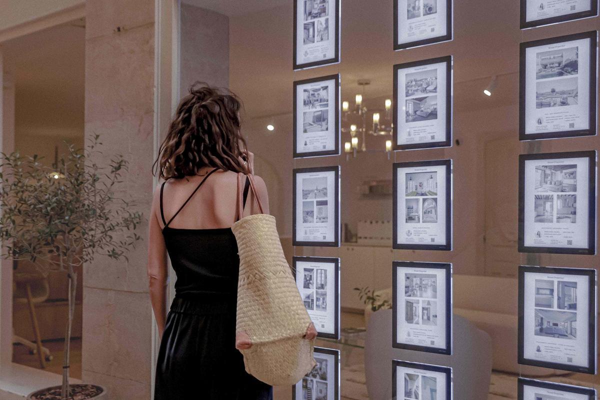 Una mujer consulta los anuncios de una inmobiliaria.