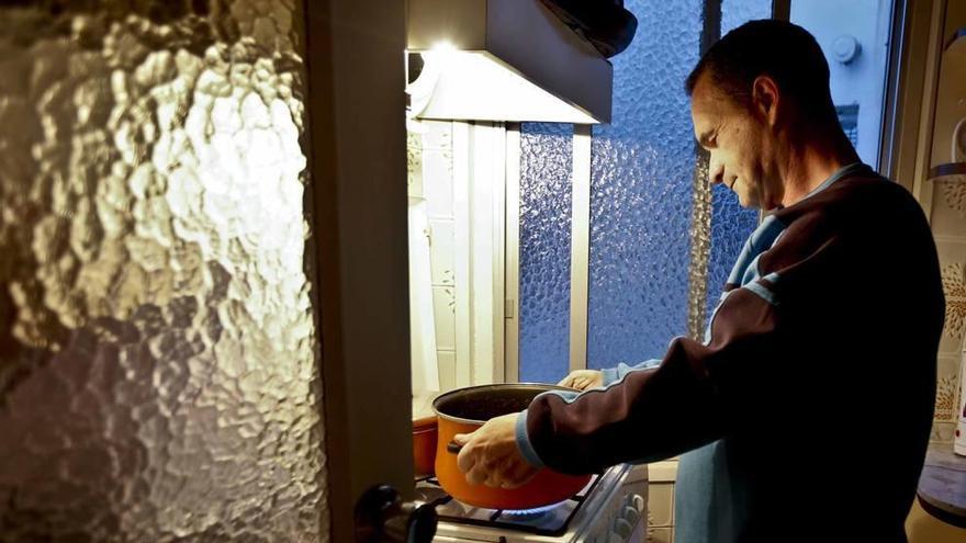 Un hombre prepara la comida en casa con las luces apagadas para ahorrar en la factura de la luz.