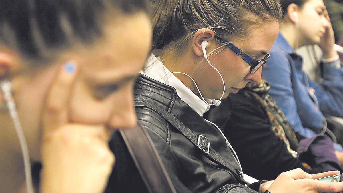 Tres jóvenes escuchando música por los auriculares en el transporte público.