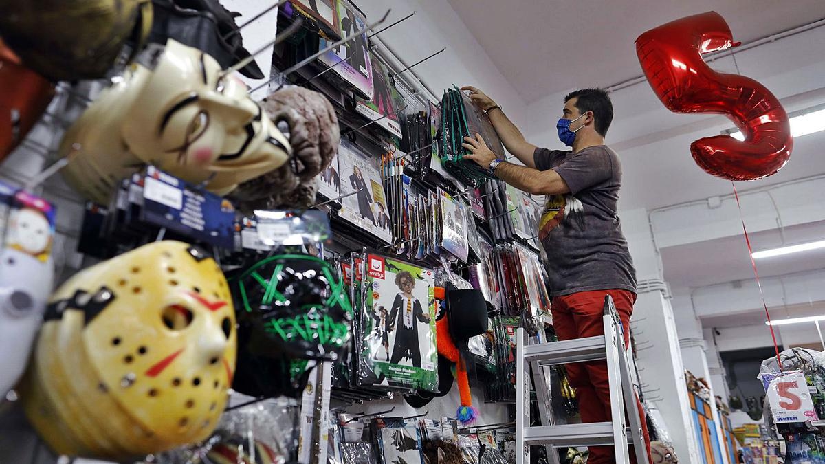 David Ariño, de la tienda Festiplanet, coloca los disfraces de Halloween en las perchas de una de las paredes de su negocio.   | M. A. MONTESINOS