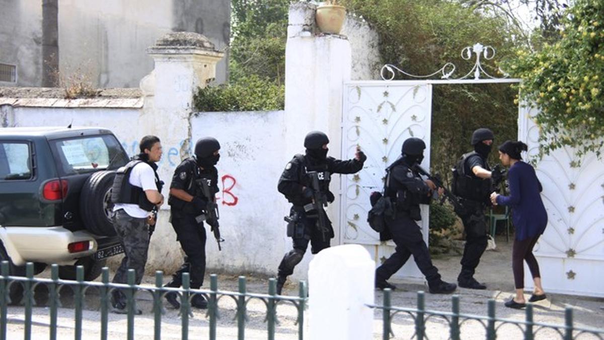 Tunisian anti-terrorism brigade personnel enter a house to take position after a shooting at the Bouchoucha military base in Tunis