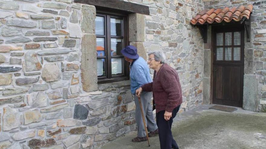 Dos vecinos de Oviñana observan la ventana por donde entraron los ladrones.