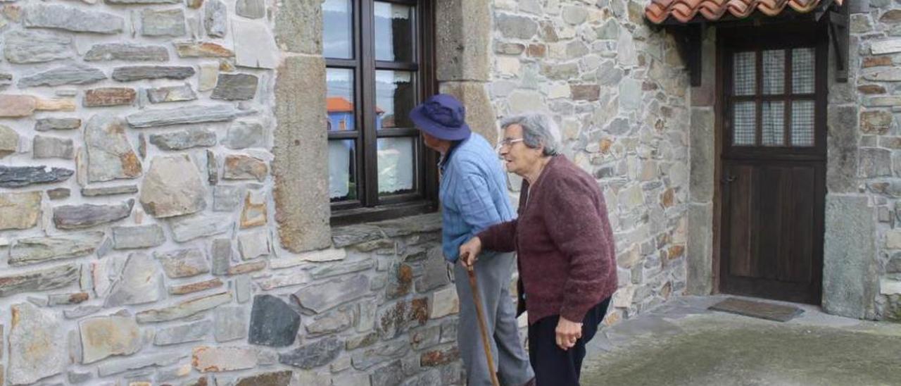 Dos vecinos de Oviñana observan la ventana por donde entraron los ladrones.