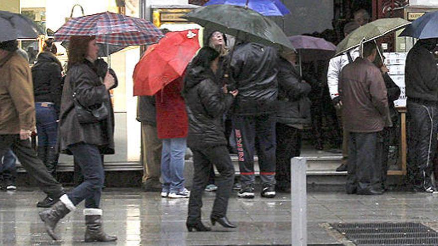 Varias personas caminan resguardadas con paraguas de la lluvia que caía este martes en Madrid