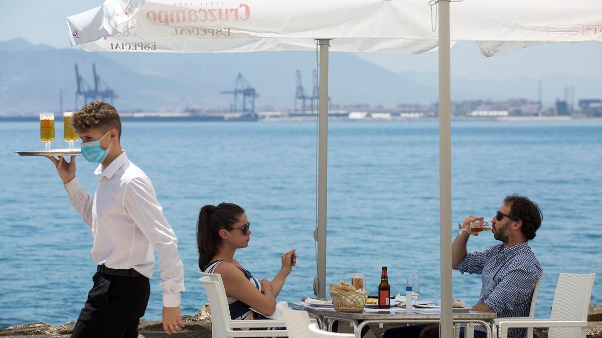 Un camarero sirve unas cervezas en la terraza de un restaurante.