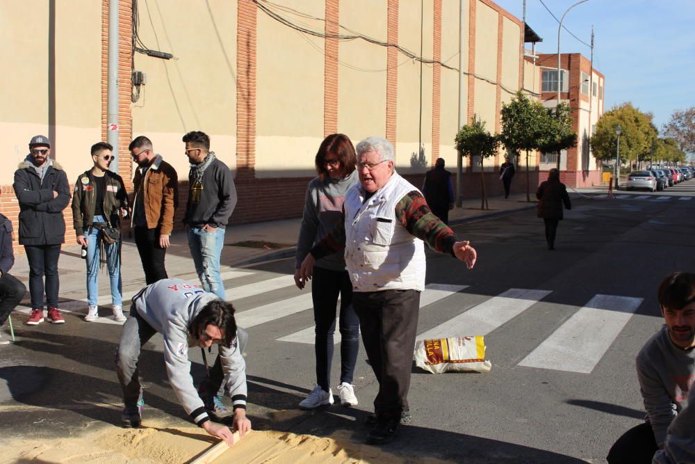 El maestro Ramón Espinosa indica cómo extender la arena protectora del asfalto.