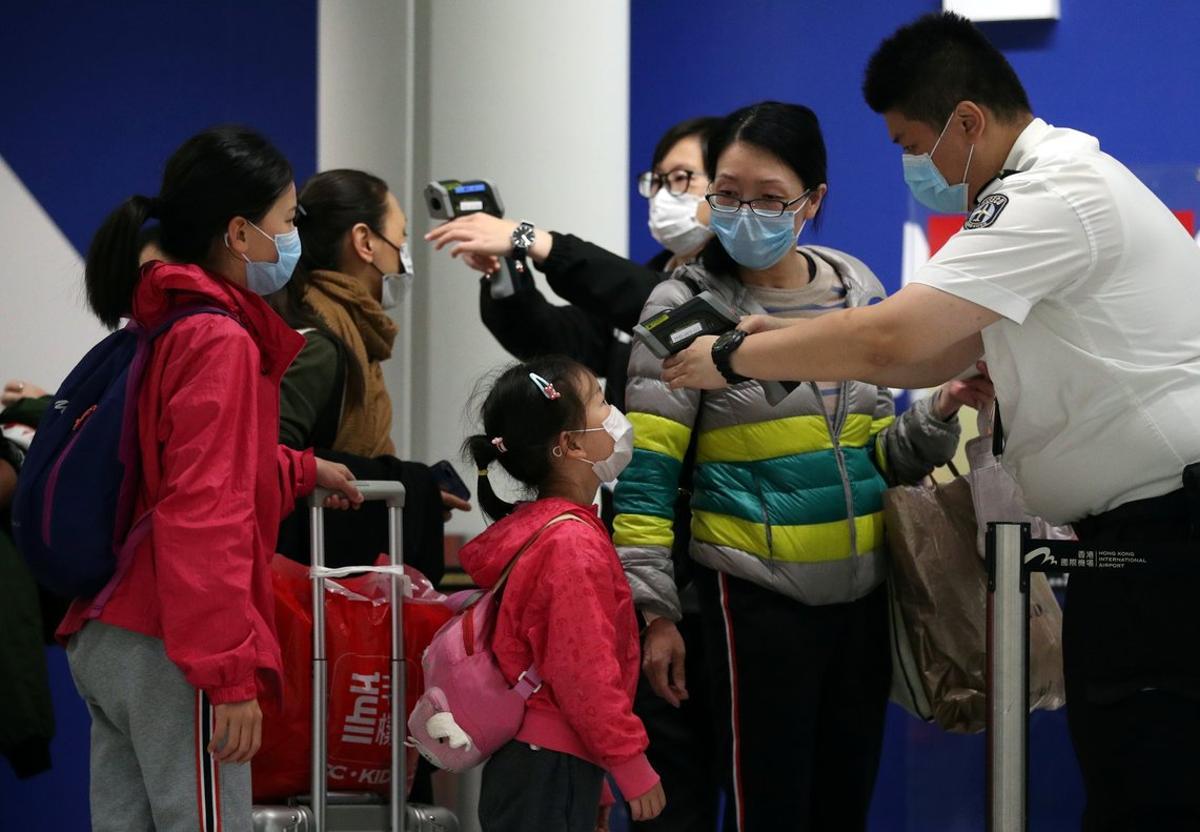 Passengers arriving into Hong Kong International Airport get their temperature checked by a worker using an infrared thermometer, following the coronavirus outbreak in Hong Kong, China, February 7, 2020. REUTERS/Hannah McKay