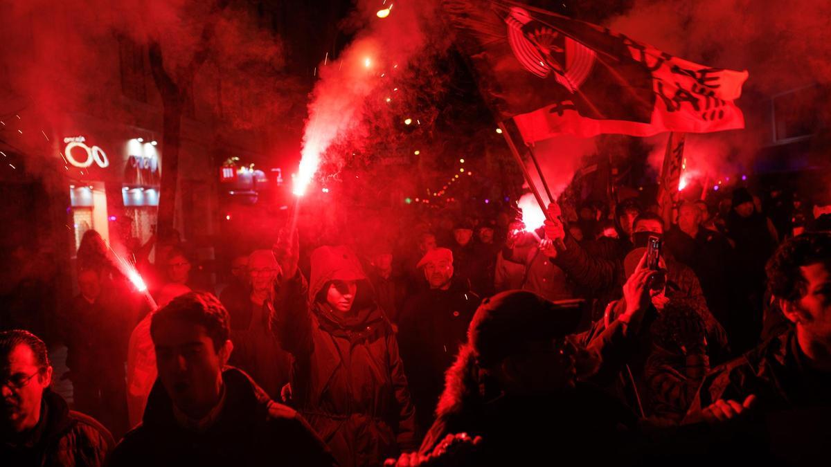 Los participantes en la protesta frente a la sede del PSOE en la calle Ferraz de Madrid encienden bengalas, este viernes.