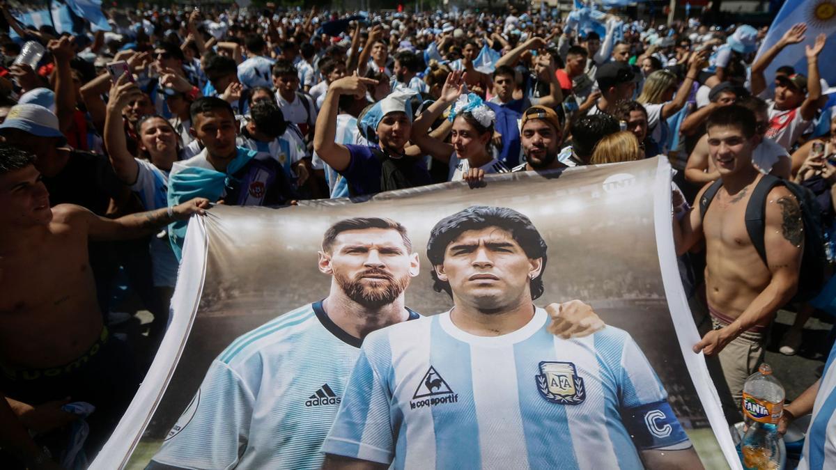 Aficionados de Argentina sostienen una bandera que representa a las estrellas del fútbol argentino Messi y Maradona, mientras se reúnen en el Obelisco para celebrar la victoria en la Copa Mundial de Qatar 2022 contra Francia en Buenos Aires.