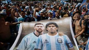Aficionados argentinos sostienen una pancarta con las imágenes de Messi y Maradona.