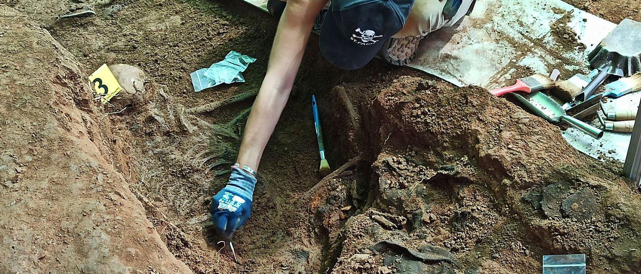 Una de las arqueólogas voluntarias trabaja en uno de los cuerpos hallados en El Rellán, en Grado. | S. ARIAS