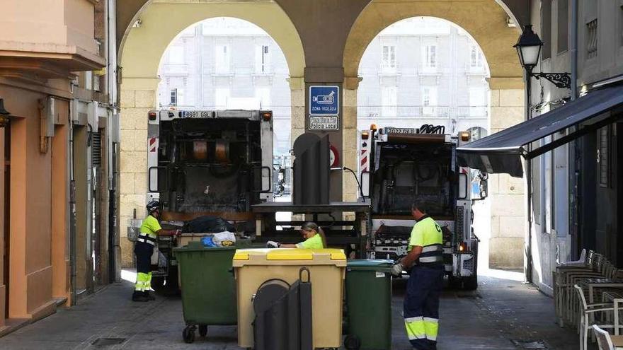 Trabajadores de la recogida, vaciando contenedores en la calle Marqués de Cerralbo.