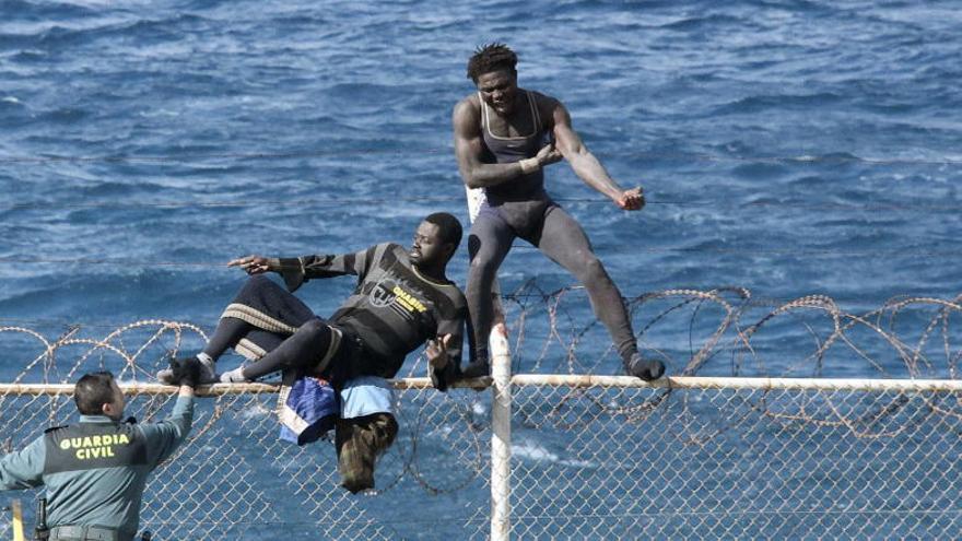 Dos inmigrantes tratan de saltar la valla de Ceuta.