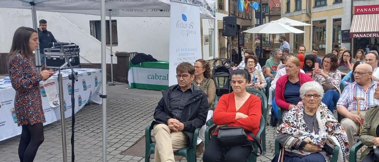 Arriba, Patricia Viesca, dirigiéndose a los participantes en el acto poético celebrado en Arenas de Cabrales. En el círculo, un momento de la proyección del vídeo «Fermentando poesía» en la plaza del Castañéu. | M. Villoria