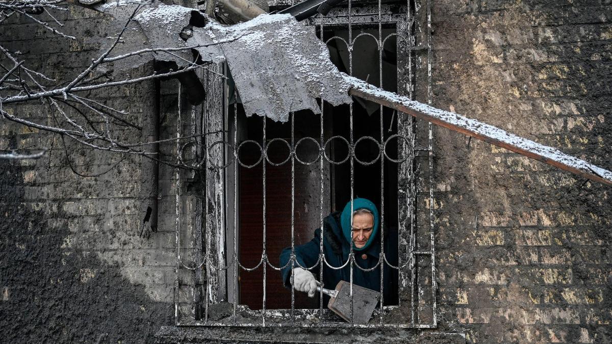 Una mujer limpia los destrozos en su vivienda atacada por un misil ruso, este lunes.