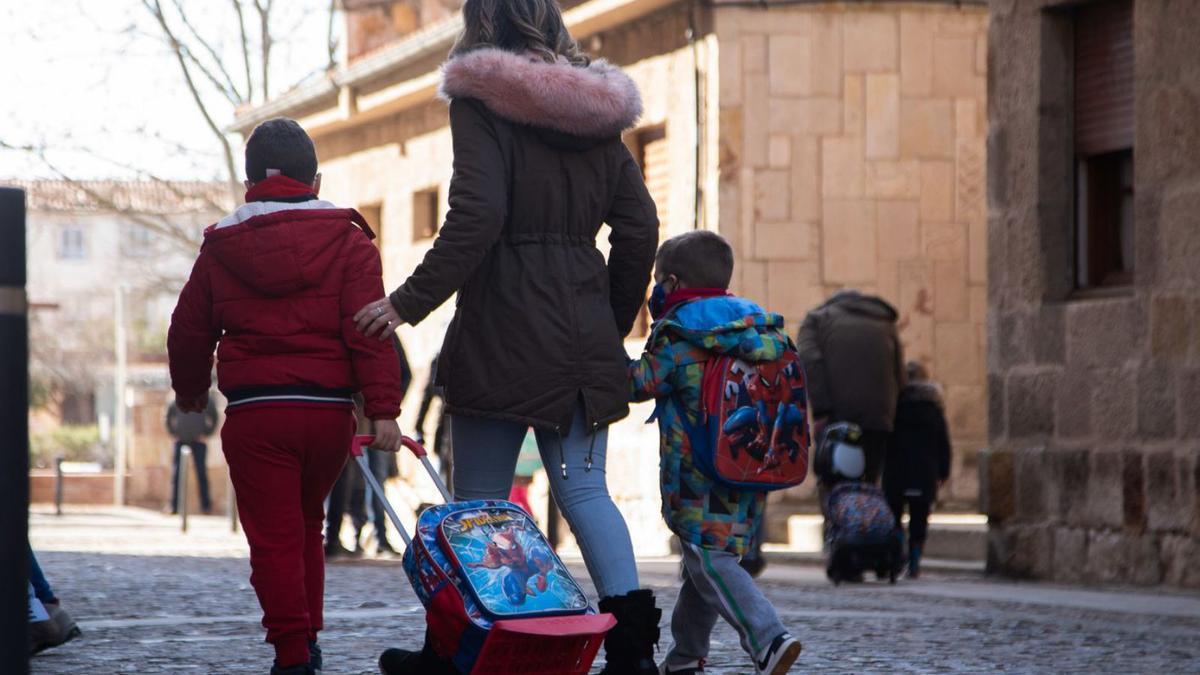 Una madre lleva a sus dos hijos al colegio.