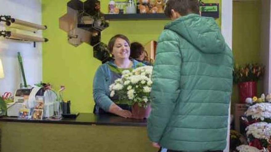 Una florista de Dragonaria muestra una maceta de crisantemos a un cliente.