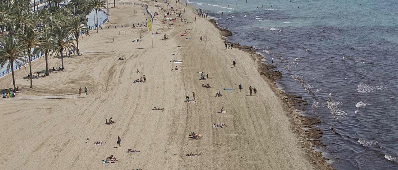La playa del Postiguet de Alicante con los primeros usuarios distanciados en la arena.
